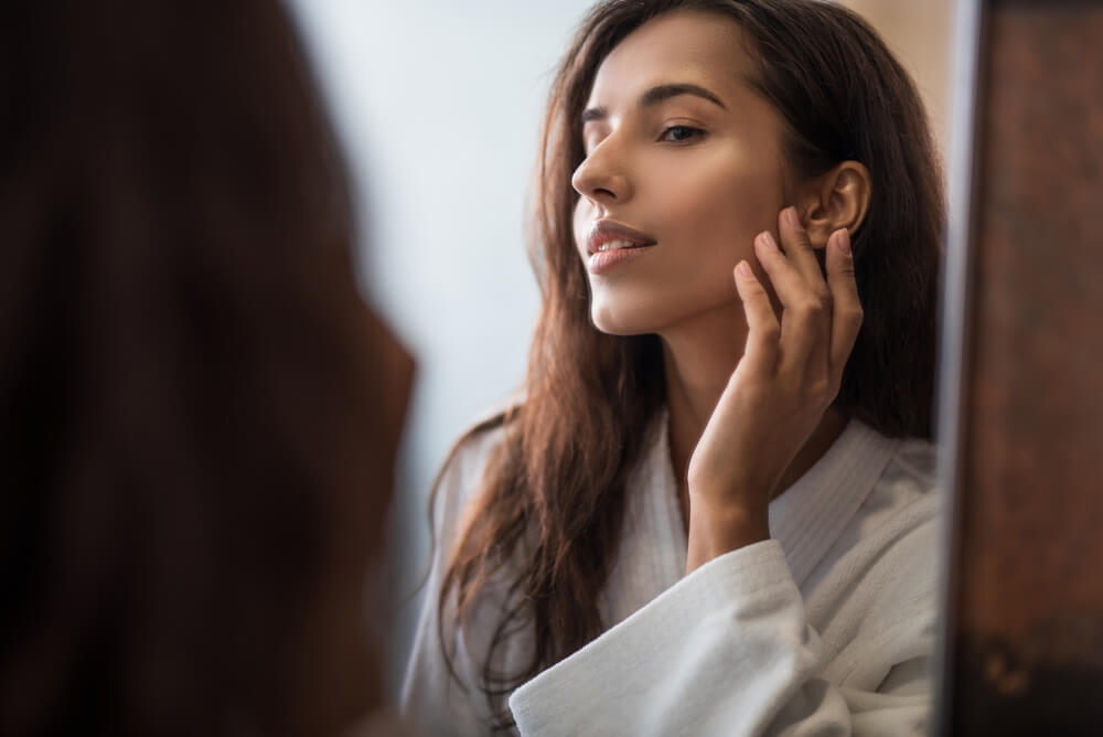 Woman looking at skin in mirror