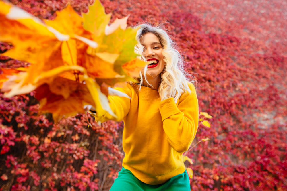 Woman playing with fall leaves