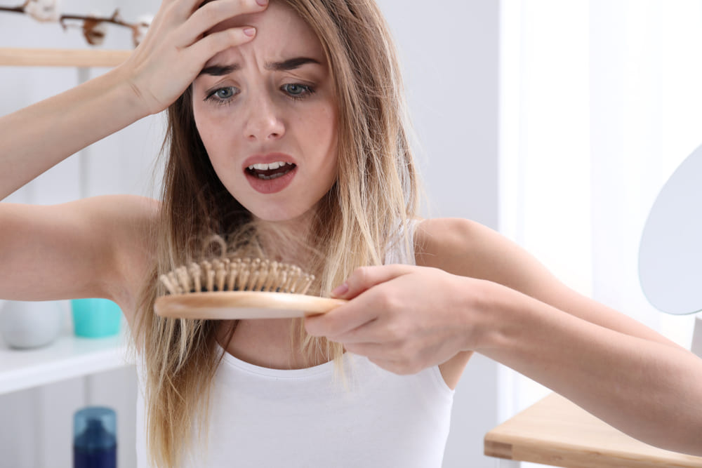 Woman looking at hair in hairbrush caused by spring shedding