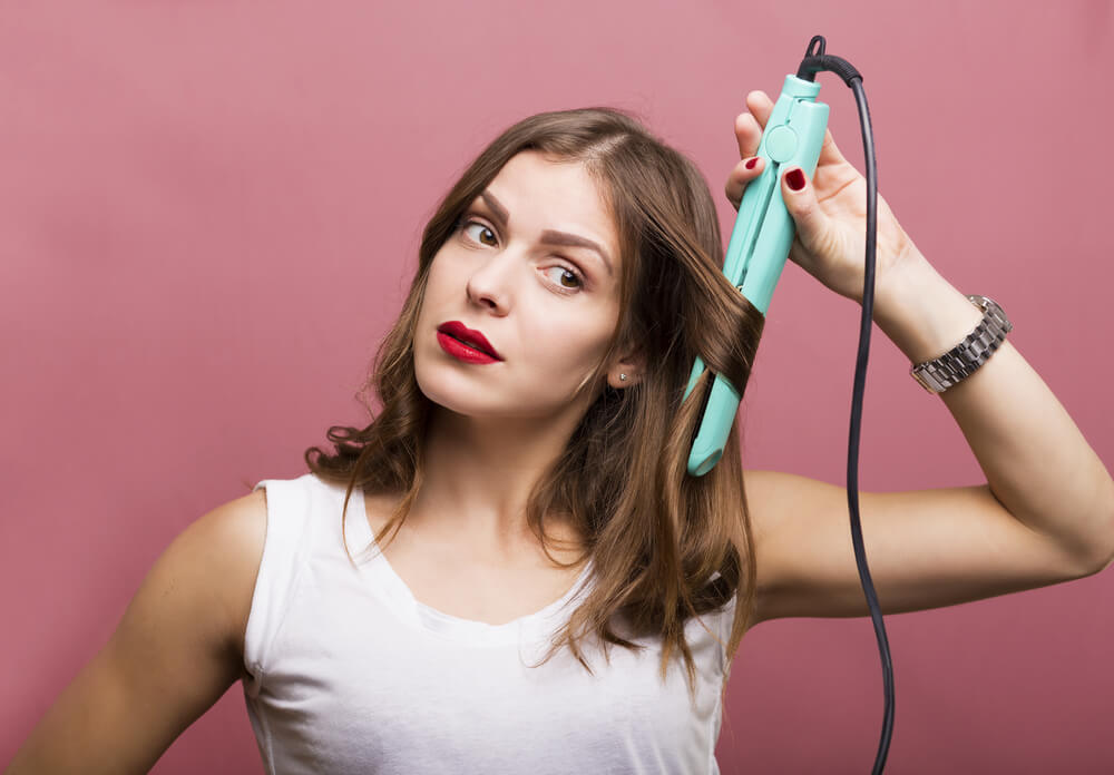 Woman curling hair with flat iron